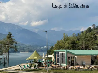 a building with tables and chairs and a lake at Appartamento Da Romina con parcheggio gratuito in Sanzeno