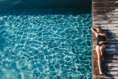 a woman sitting on a porch next to a swimming pool at Hotel Rudolf in Brunico