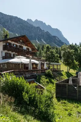 a building with tables and umbrellas in a field at Baita Fraina in Cortina dʼAmpezzo