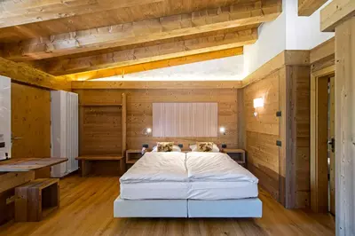 a bedroom with a bed in a room with wooden walls at Baita Fraina in Cortina dʼAmpezzo