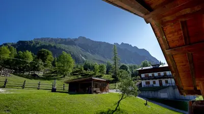 a house in a field with mountains in the background at Baita Fraina in Cortina dʼAmpezzo