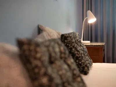 a bed with a pillow and a lamp on a table at Villa Atelier Baron Killi in Caldaro