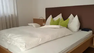 a large white bed with green pillows on it at Garni Raffein in Lana