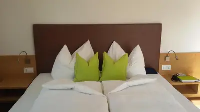 a bed with green and white pillows on it at Garni Raffein in Lana