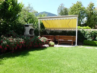 a bench in a garden with a yellow canopy at Garni Raffein in Lana
