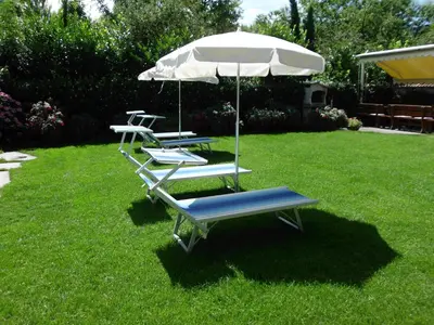 two lounge chairs and an umbrella in a yard at Garni Raffein in Lana