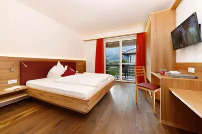 a bedroom with a bed and a desk and a television at Garni Raffein in Lana