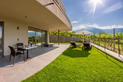 a patio with grass and a table and chairs at Apartments Lichtenberg in Lagundo