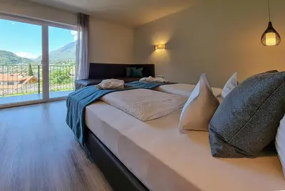 a bedroom with two beds and a large window at Apartments Lichtenberg in Lagundo