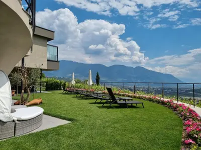 a row of chairs and tables on a lawn with a view at Apartments Lichtenberg in Lagundo