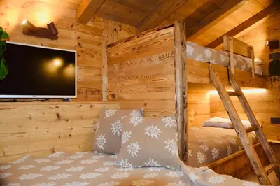 a bedroom in a log cabin with a tv and a bunk bed at iFlat Chalet Carole Ortisei in Ortisei