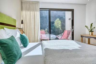 a bedroom with a bed and a balcony with a table at Castanea Appartements in Caines