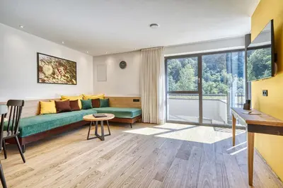 a living room with a green couch and a large window at Castanea Appartements in Caines