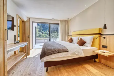 a bedroom with a bed and a large window at Castanea Appartements in Caines