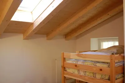 a bedroom with a wooden bed with a skylight at LA CIESA DEI SIORI in Alleghe