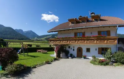 a white house with a garden and mountains in the background at Gandlerhof in Valdaora