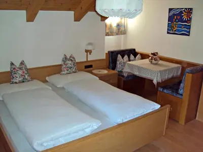 a bedroom with two beds and a table and chairs at Gandlerhof in Valdaora