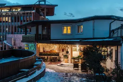 a house with a swimming pool in front of a building at Hotel Olimpia in Cortina dʼAmpezzo