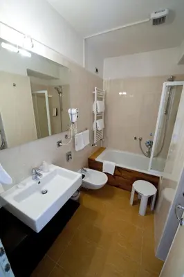 a bathroom with a sink and a tub and a toilet at Hotel Olimpia in Cortina dʼAmpezzo