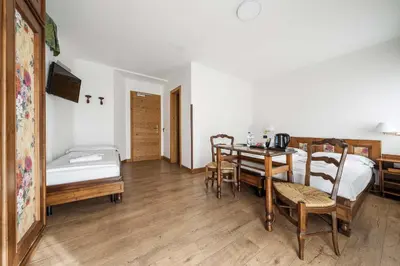 a room with a table and chairs and a bed at Hotel Olimpia in Cortina dʼAmpezzo
