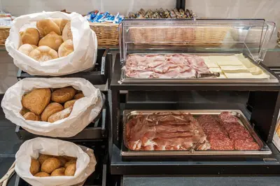 a buffet with different types of bread and meat at Hotel Olimpia in Cortina dʼAmpezzo