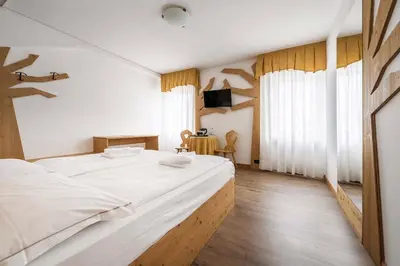 a bedroom with a large white bed and a table at Hotel Olimpia in Cortina dʼAmpezzo