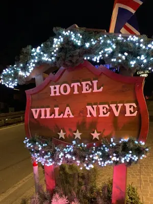 a sign for a hotel with christmas lights at Meuble Villa Neve in Cortina dʼAmpezzo