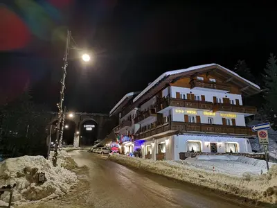 a building on a snowy street at night at Meuble Villa Neve in Cortina dʼAmpezzo