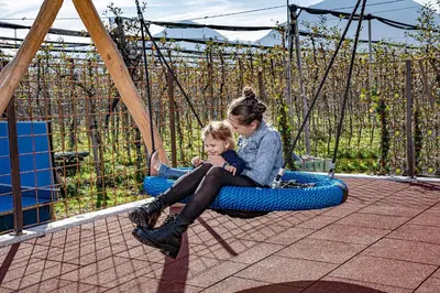 a woman and a child sitting on a swing at Auhof in Merano