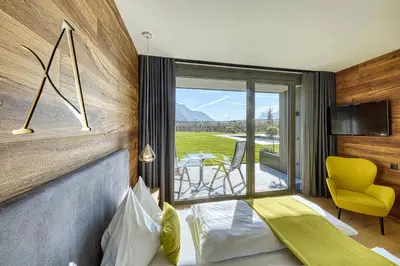 a hotel room with a bed and a view of a patio at Auhof in Merano