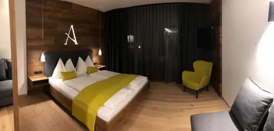 a bedroom with a large bed and a yellow chair at Auhof in Merano