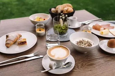 a table with plates of food and a cup of coffee at Auhof in Merano