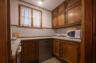 a kitchen with wooden cabinets and a microwave at Casa Regoiettes in San Vito di Cadore