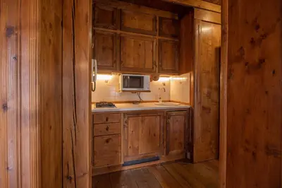 a kitchen with wooden cabinets and a sink and a microwave at Casa Regoiettes in San Vito di Cadore