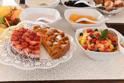 a table with a plate of food and a plate of fruit at Hotel Juliane in Merano