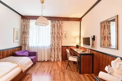 a hotel room with a bed and a desk with a computer at Hotel Juliane in Merano
