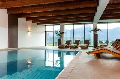 a swimming pool with lounge chairs and windows at Bio & Wellnesshotel Pazeider - Healing Garden above Meran in Marlengo