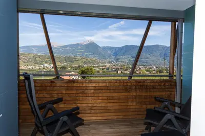 two chairs on a balcony with a view of mountains at Bio & Wellnesshotel Pazeider - Healing Garden above Meran in Marlengo