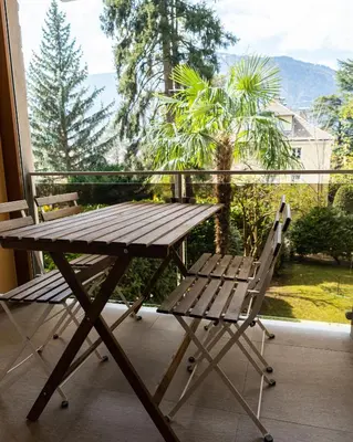 a picnic table and a chair on a balcony at Flow Apartments Astoria in Merano