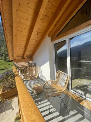a porch with wicker chairs and a wooden ceiling at B&B La Casa del Sole in Ziano di Fiemme