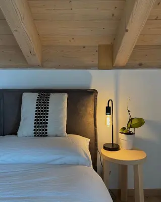 a bedroom with a bed and a table with a lamp at B&B La Casa del Sole in Ziano di Fiemme