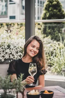 a woman sitting at a table holding a wine glass at Aktiv & Genusshotel Lodenwirt in Vandoies