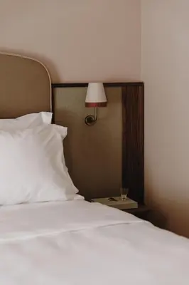 a bed with a white pillow and a lamp on a table at Parkhotel Mondschein, a Member of Design Hotels in Bolzano