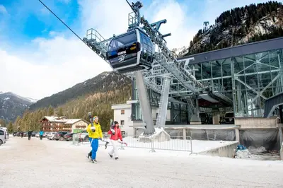 a couple of people walking down a ski lift at Hotel Villa Rosella Park & Wellness in Canazei