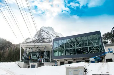a building in the snow with a mountain in the background at Hotel Villa Rosella Park & Wellness in Canazei