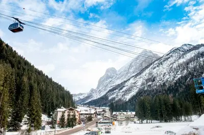 a ski resort with a ski lift in the mountains at Hotel Villa Rosella Park & Wellness in Canazei