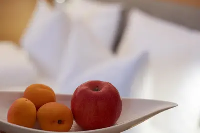 a plate with an apple and three tangerines on it at Hotel Post Gries in Bolzano