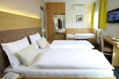 a hotel room with two beds and a desk at Hotel Post Gries in Bolzano