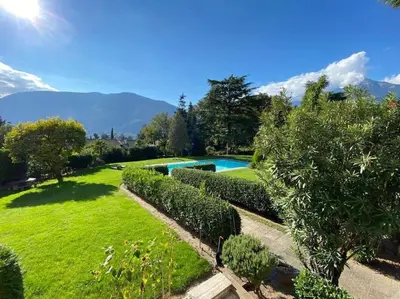 a garden with a swimming pool and some bushes at Garden Pool Apartment in Merano