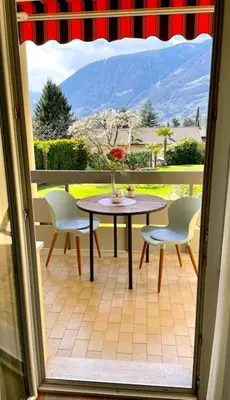 a patio with a table and chairs and a window at Garden Pool Apartment in Merano